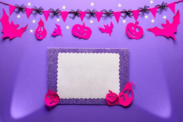 Kreatywna ściana Halloween w kolorze fioletowym, czerwonym i czarnym, mieszkanie leżało z kopią. Reflektory, papierowe figurki nietoperzy i dynie z latarnią, girlanda z pająkami i papier z przestrzenią do kopiowania.