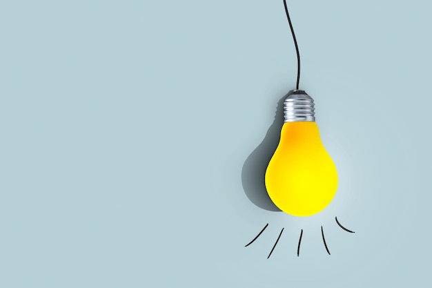 Zdjęcie kreatywna żółta żarówka zawiesza się i świeci na niebieskim tle myśl inaczej koncepcja udany projekt uczenie się i myśli