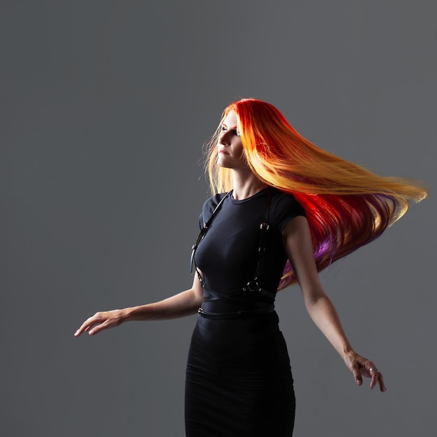 Kreatywne farbowanie włosów młodej kobiety o jasnych rudych włosach z żółtymi i fioletowymi pasmami włosów w fli