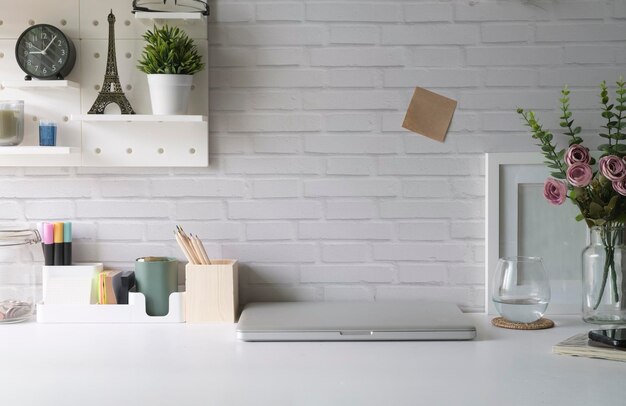 Kreatywne miejsce pracy z doniczką na laptopa i papeterią na białym stole