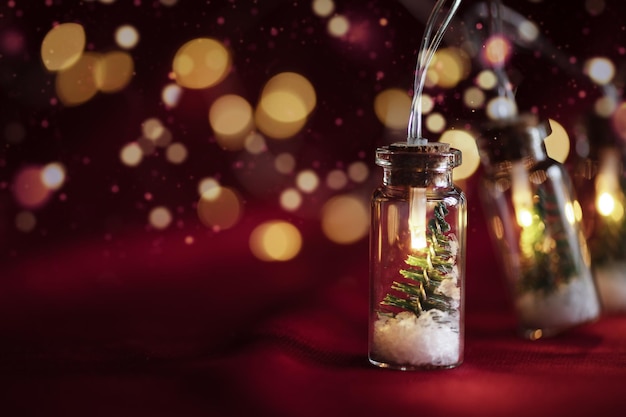 Kreatywne świąteczne lampki wiankowe z choinką bokeh w szklanym słoju ze śniegiem