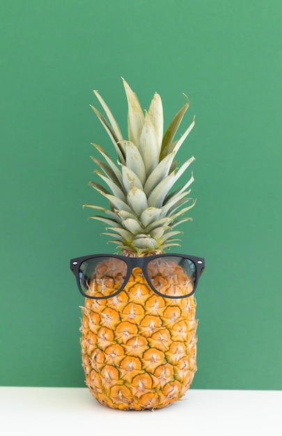 Kreatywny ananas z okularami przeciwsłonecznymi na kolorowym tle letnie wakacje na plaży