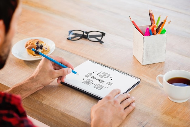 Kreatywny biznesmen piszący notatki na notebooku przeciwko responsywnemu projektowi doodle