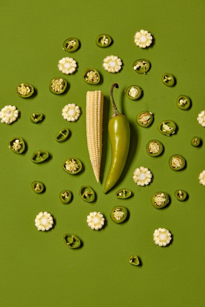 Kreatywny układ świeżej, pięknej papryczki chili i mini kukurydzy na zielonym tle Minimalna koncepcja jedzenia