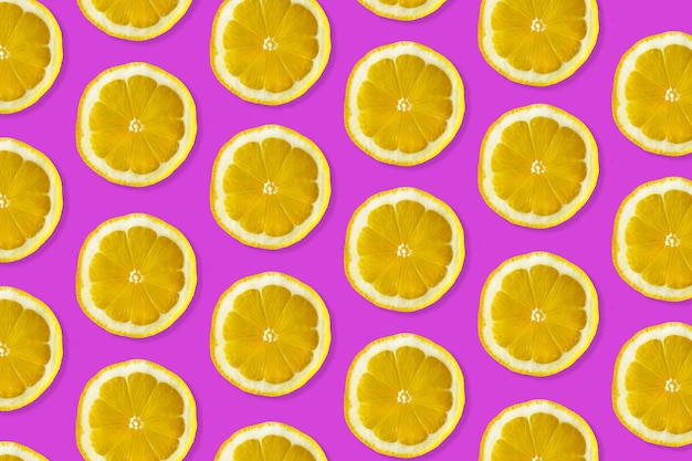 Kreatywny wzór wykonany z cytryny widok z góry owoców świeżych plasterków cytryny na kolorowym fioletowym tle