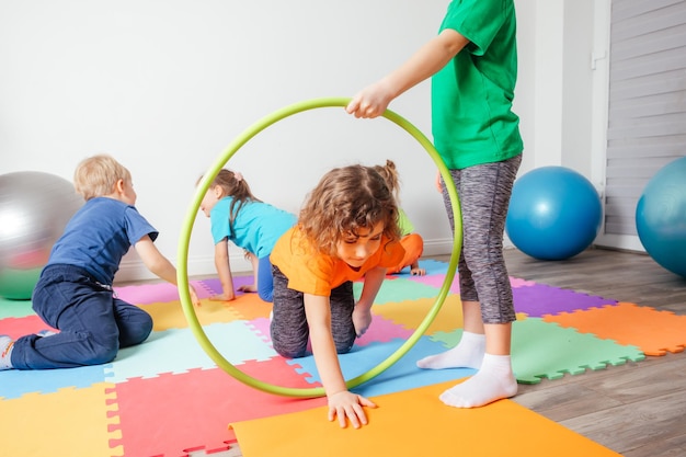 Kręcona dziewczyna czołgająca się po kolorowej podłodze przez hula-hoop