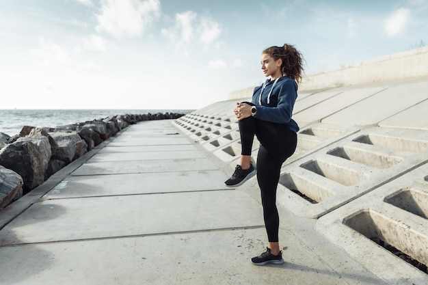 Kręcone sportowe kobiety w sportowej odzieży rozgrzewającej ciało przed treningiem na miejskiej plaży Zdrowy styl życia