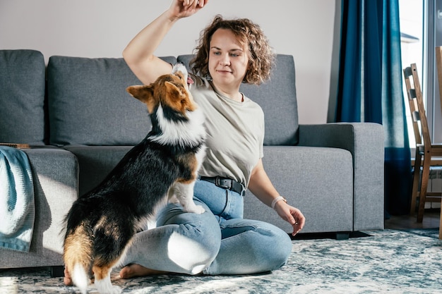 Kręcone Włosy Zadowolona Wesoła Boso Kobieta Z Psem Corgi Trening Posłuszeństwa Karmienie Zwierząt Siedzących I Bawiących Się