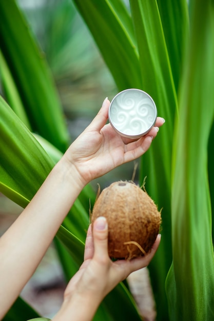 Krem kokosowy. Bliska trzymając się za ręce kokos i słoik śmietany
