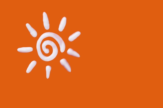Krem przeciwsłoneczny w kształcie słońca na pomarańczowym tle Kreatywny pomysł kremu do opalania
