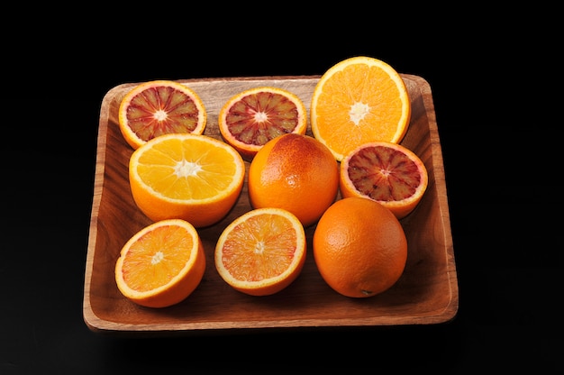 Krew pomarańcze całe i pokrojone na pół na drewnianej misce