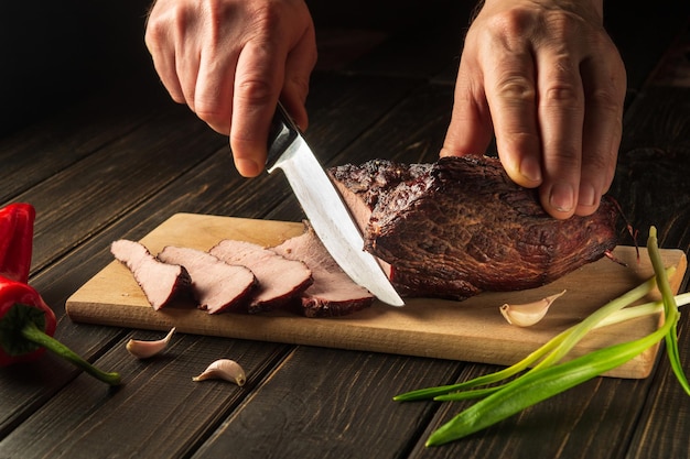 Krojenie gotowanego mięsa na desce kuchennej na obiad Zbliżenie szefa kuchni z nożem Chłopskie jedzenie