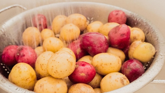 Krok po kroku. Małe czerwone i złote ziemniaki myte w durszlaku.