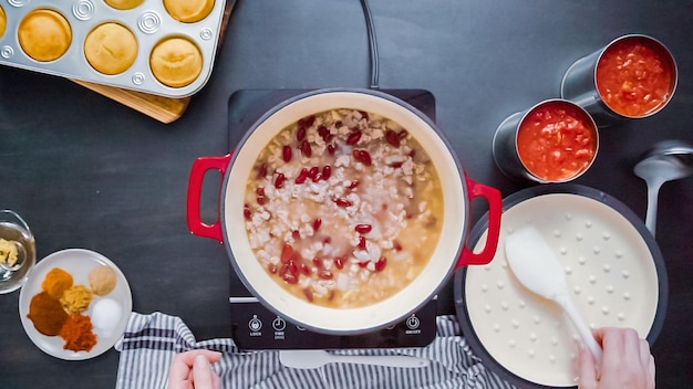 Krok po kroku. Widok z góry. Gotowanie chili z indyka w emaliowanym żeliwnym piekarniku.