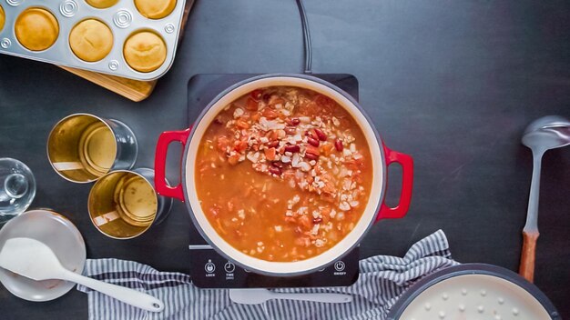 Krok po kroku. Widok z góry. Mieszanie chili z indyka w emaliowanym żeliwnym piecu holenderskim.