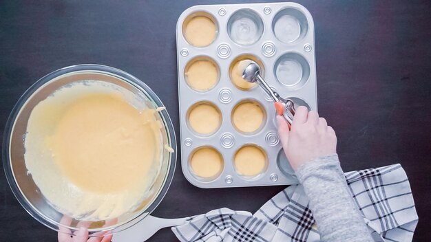 Krok po kroku. Widok z góry. Napełnianie metalowej patelni do muffinek ciastem kukurydzianym.