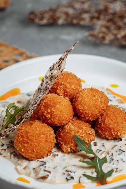 Zdjęcie krokety ziemniaczane, puré ziemniaków, kulki panowane i smażone, podawane z różnymi sosami