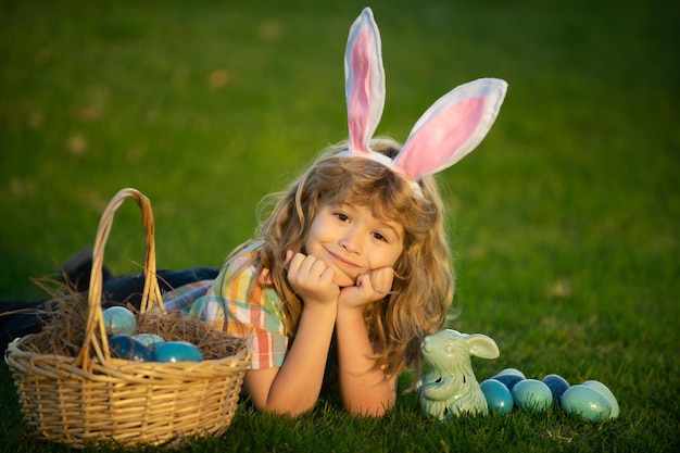 Króliczek z uszami królika chłopiec chłopiec z pisanki w koszyku na zewnątrz dziecko leżące na traw...