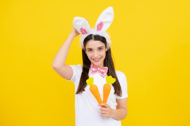 Królik dziewczyna z zabawkarską marchewką Rozochocona uśmiechnięta dziewczyna świętuje Wielkanoc w króliczych uszach