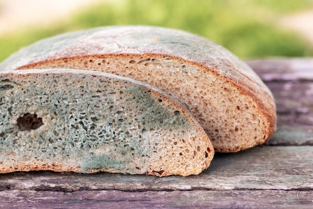 Kromka chleba pokryta pleśnią na drewnianej powierzchni