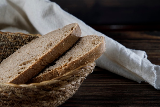 Kromki rustykalnego chleba w wiklinowej misce na drewnianym stole
