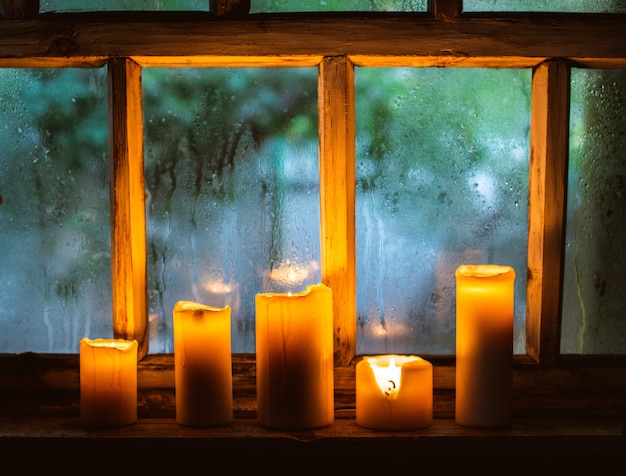 Zdjęcie krople deszczu na oknie i płonące świece