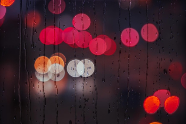 krople deszczu na oknie w deszczowe dni i tło latarni ulicznych