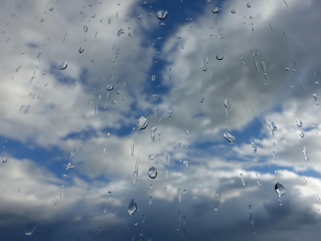 Krople deszczu na oknie z chmurami i tłem nieba po deszczu