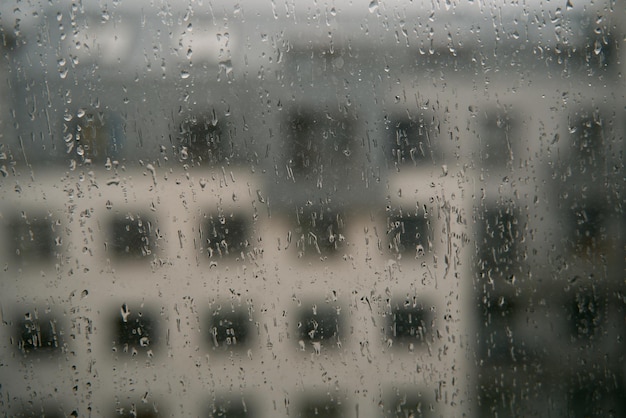 Zdjęcie krople deszczu na oknie z tłem kamienicy koncepcja pozostania w domu, gdy na zewnątrz jest zła pogoda przytulny widok na wnętrze w deszczową pogodę