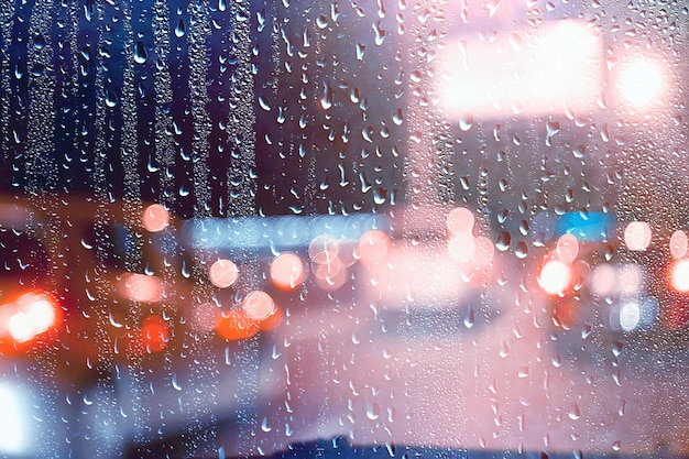 krople na szybie auto droga deszcz jesienna noc / abstrakcyjne jesienne tło w mieście, ruch samochodowy, romantyczna podróż samochodem