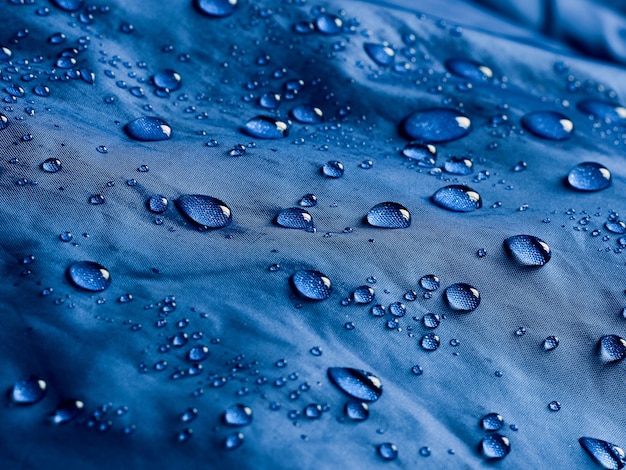Krople wody na wodoodpornej tkaninie membranowej. Widok szczegółów tekstury niebieskiej tkaniny wodoodpornej.