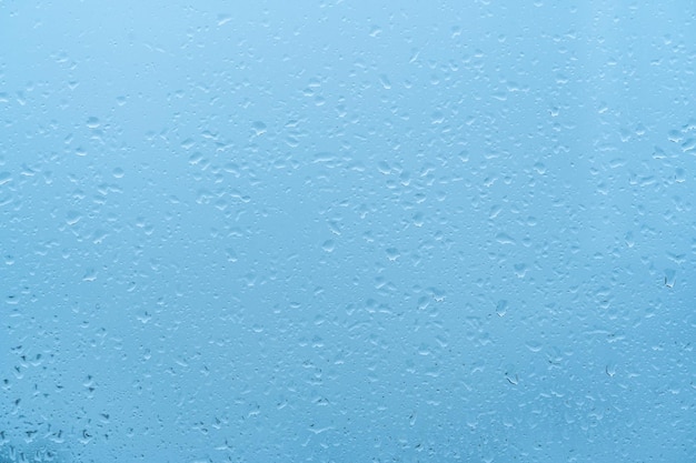 Krople wody w tle Krople deszczu na oknie niebieskie tło Krople wody deszczowej o świcie z niebieskim światłem na szklanym tle niebieskie tło krople szkło abstrakcyjna tekstura