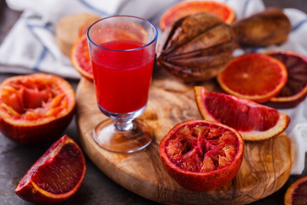 Krwistoczerwony, świeżo wyciśnięty sok pomarańczowy, na drewnianej desce.