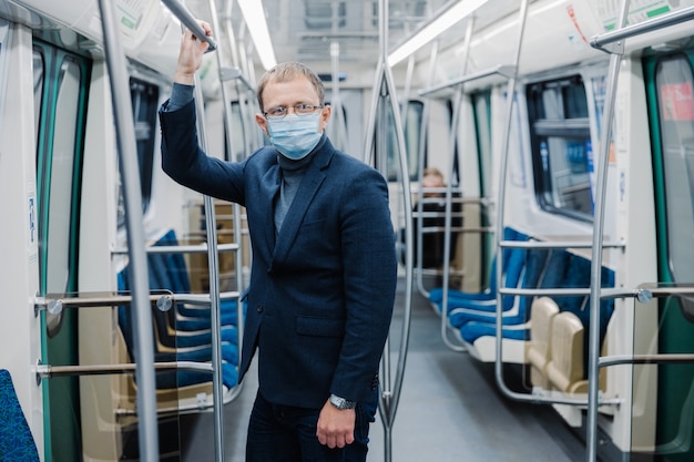 Kryzys koronawirusowy w 2020 r. Mężczyzna dojeżdża do pracy w pustym podziemiu, korzysta z transportu publicznego, używa ochronnej maski na twarz przed wirusem, nosi ochronną maskę chirurgiczną w okresie kwarantanny