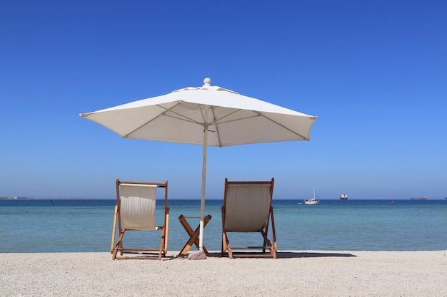 Krzesła plażowe z parasolem skierowanym w stronę oceanu