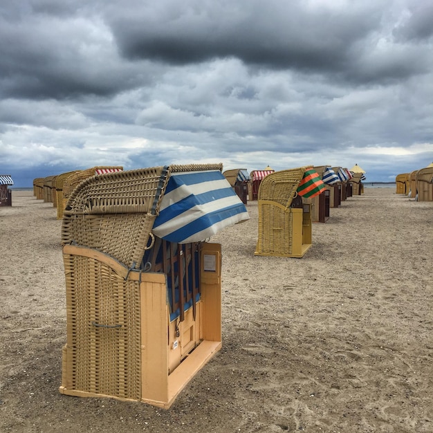 Zdjęcie krzesła z kapturem na plaży na chmurnym niebie