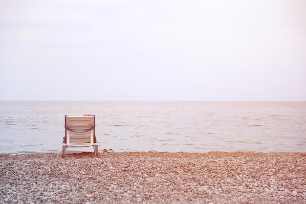 Krzesło na brzegu kamyków z morzem i plażą