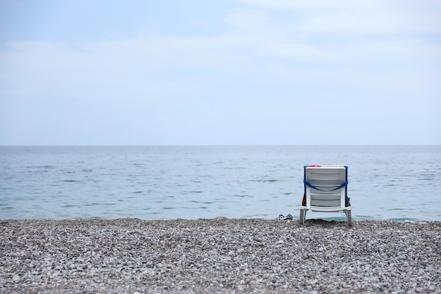 Krzesło na brzegu kamyków z morzem i plażą