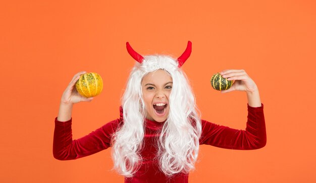 Krzyczące dziecko diabła z białymi włosami trzymaj warzywo dyni nosić kostium rogów imp na imprezie halloween, happy halloween.