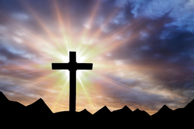 Krzyż Jezusa Chrystusa na niesamowitym tle górskiego zachodu słońca z dramatycznym oświetleniem i promieniami słońca