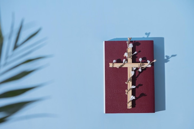 Krzyż ozdobiony kwiatami z Świętą Biblią na niebieskim tle Wielkanocna koncepcja minimalistyczna