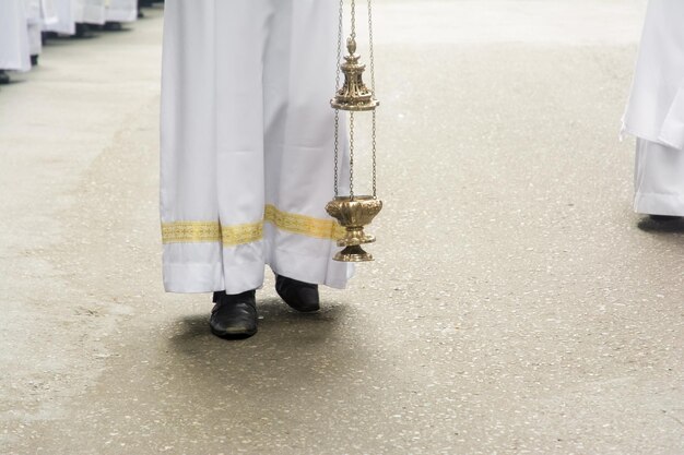 Zdjęcie ksiądz używa palnika do wydychania kadzidła podczas procesji corpus christi