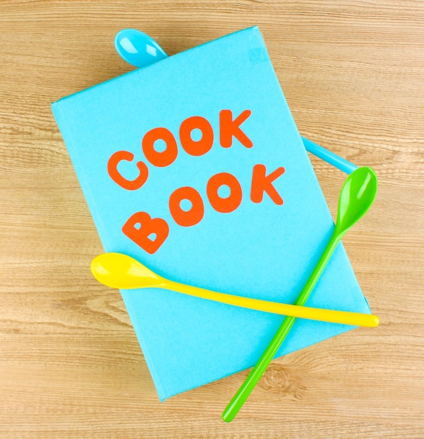Zdjęcie książka kucharska i przybory kuchenne na drewnianym tle