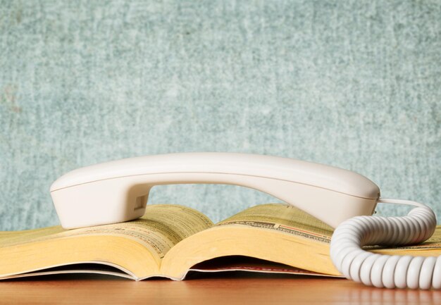 Zdjęcie książka telefoniczna i uchwyt telefoniczny na drewnianym stole
