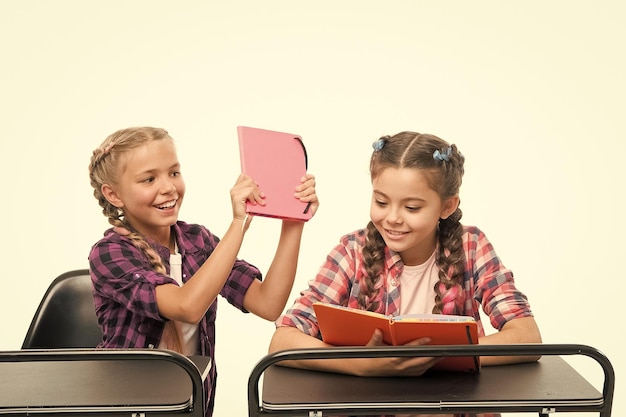 Książki nie służą do bicia Niegrzeczna dziewczynka rozpieszcza koleżankę z klasy za walkę o książki na białym tle Zabawne dziecko bawi się podczas gdy mały uczeń czyta książkę Książki edukacyjne dla uczniów