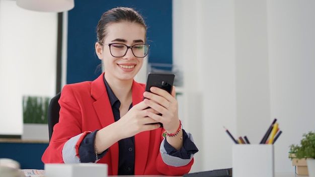 Księgowy firmy sprawdzający wiadomość tekstową na smartfonie po pracy nad rozwojem firmy. Konsultant ds. sprzedaży przeglądający internet w telefonie, planujący strategię marketingu finansowego w biurze.