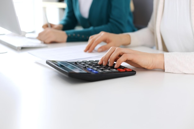 Księgowy sprawdzający sprawozdanie finansowe lub obliczający za pomocą kalkulatora dochód do zbliżenia rąk w formularzu podatkowym