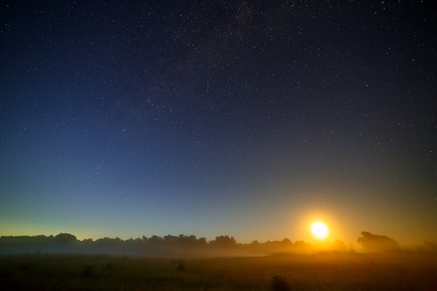 Księżyc na tle rozgwieżdżonego nocnego nieba.