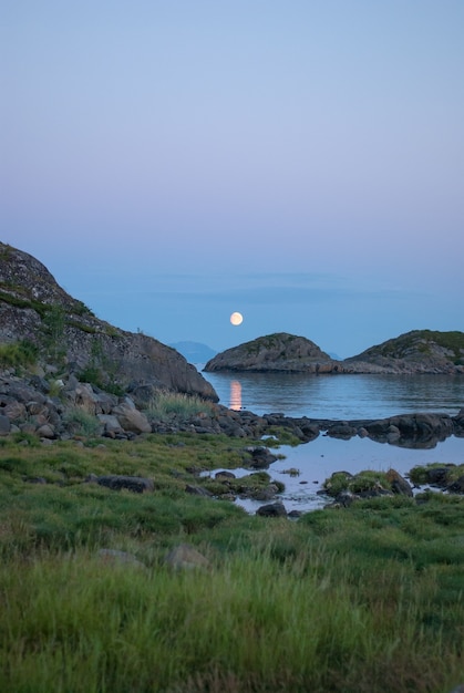 Zdjęcie księżyc w pełni nad morzem i skałami, lofoty, norwegia