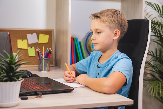 Kształcenie online na odległość Uczeń uczy się w domu z laptopem i odrabia lekcje w szkole